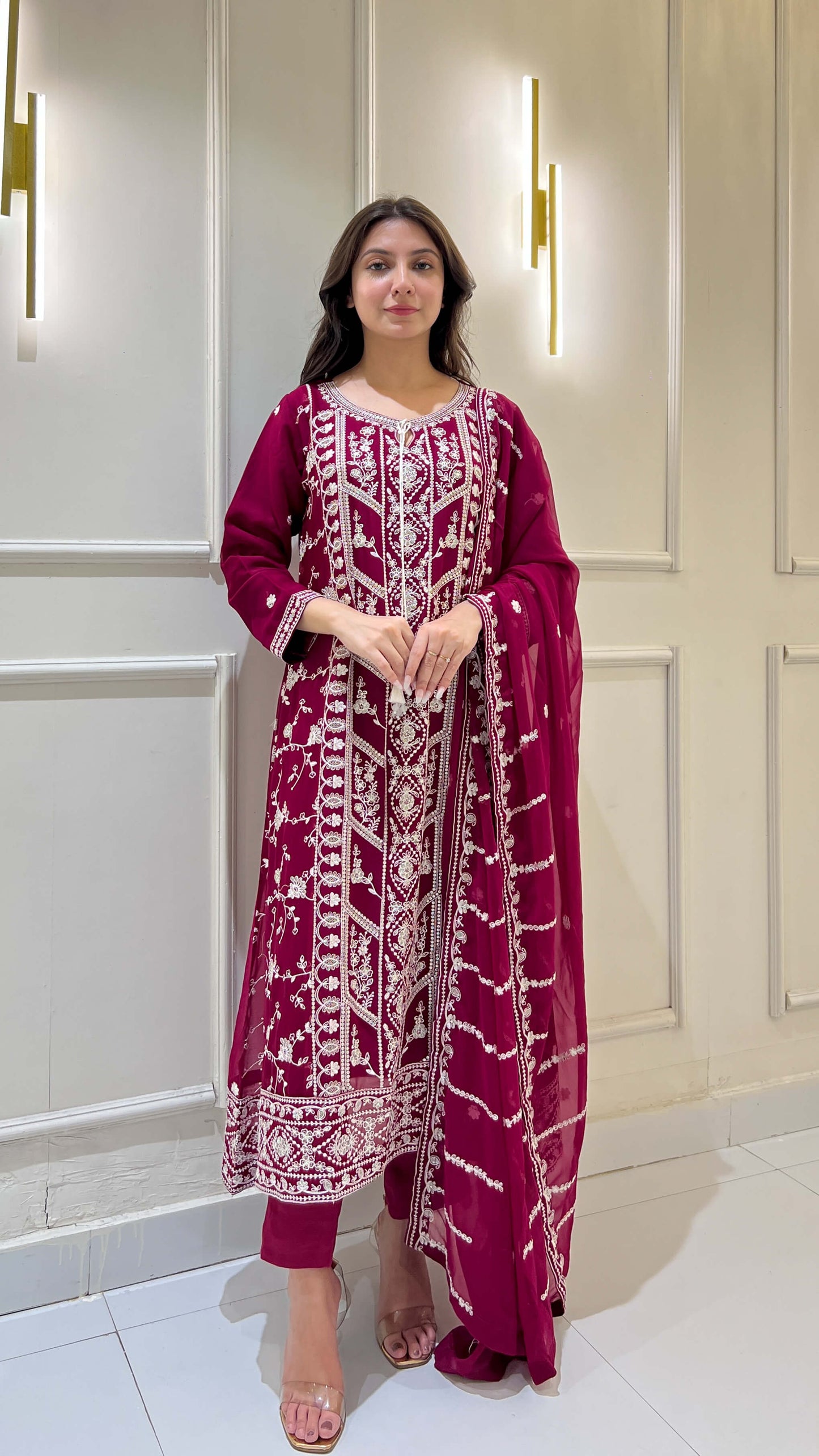 Woman posing in magenta chiffon suit with white embroidery details