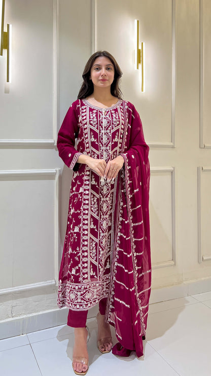 Woman posing in magenta chiffon suit with white embroidery details