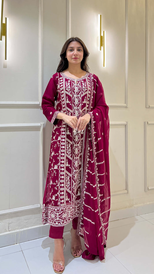 Woman posing in magenta chiffon suit with white embroidery details